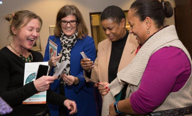 Four women standing in group viewing photos
