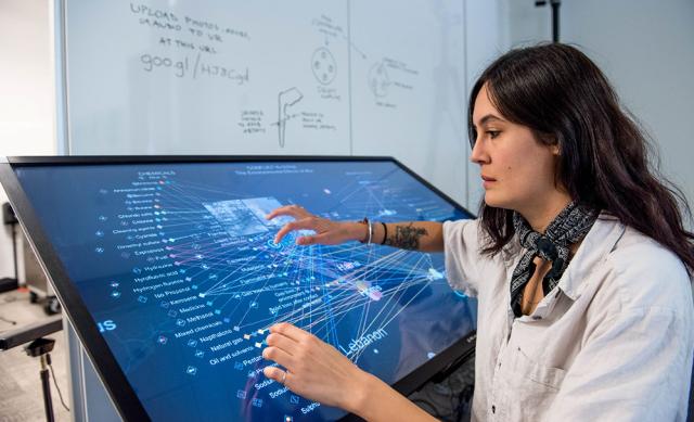 Woman using extra large touch screen for research