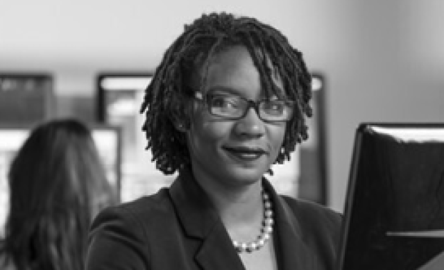 Black and white close up of Black woman with braided hair in an office 