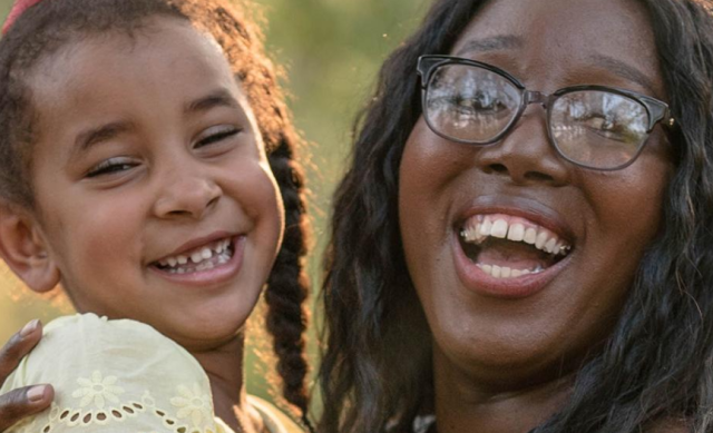 Close up of woman student smiling and holding her daughter