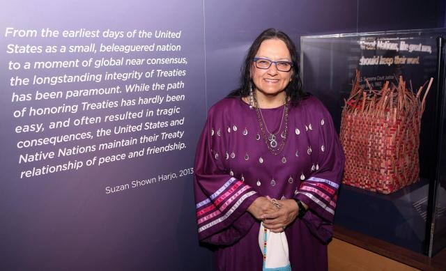 Suzan Shown Harjo (Hodulgee Muscogee/Southern Cheyenne) standing in front of exhibit at the National Museum of the American Indian