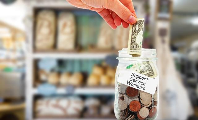 Tip jar that says "Support Service Workers" with hand above it adding one dollar.