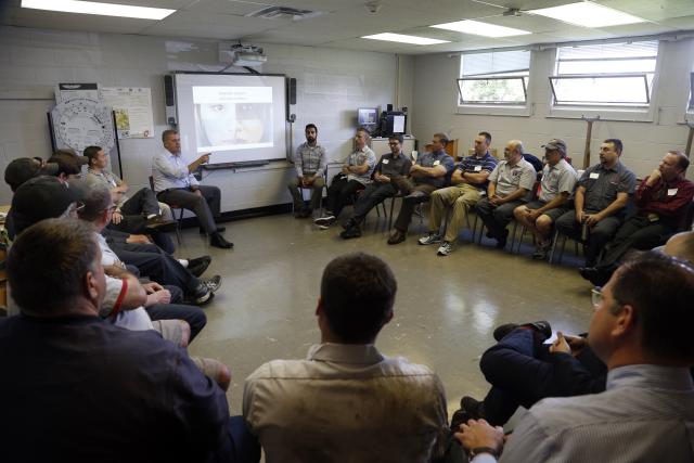 Men sitting in chairs in a circle at an Ally facilitation