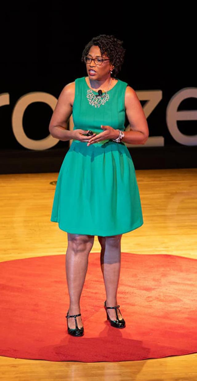Dr. Deena Chisolm standing on stage delivering a TED Talk