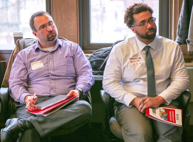 two men listen while seated