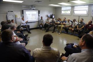 Men sitting in chairs in a circle at an Ally facilitation