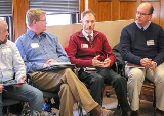 Four men sitting in large circle having discussion