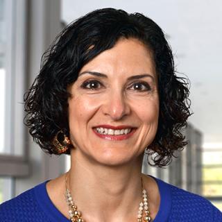 Arwa Shana'ah smiling wearing a blue shirt and orange beaded necklace.