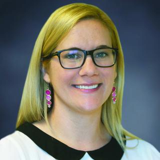 Nikole Patson standing in front of a dark gray background. 