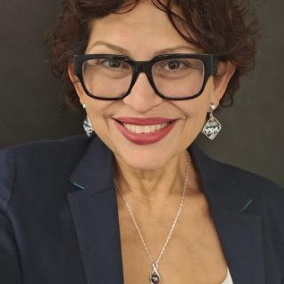 Woman smiling with large black glasses and red lipstick