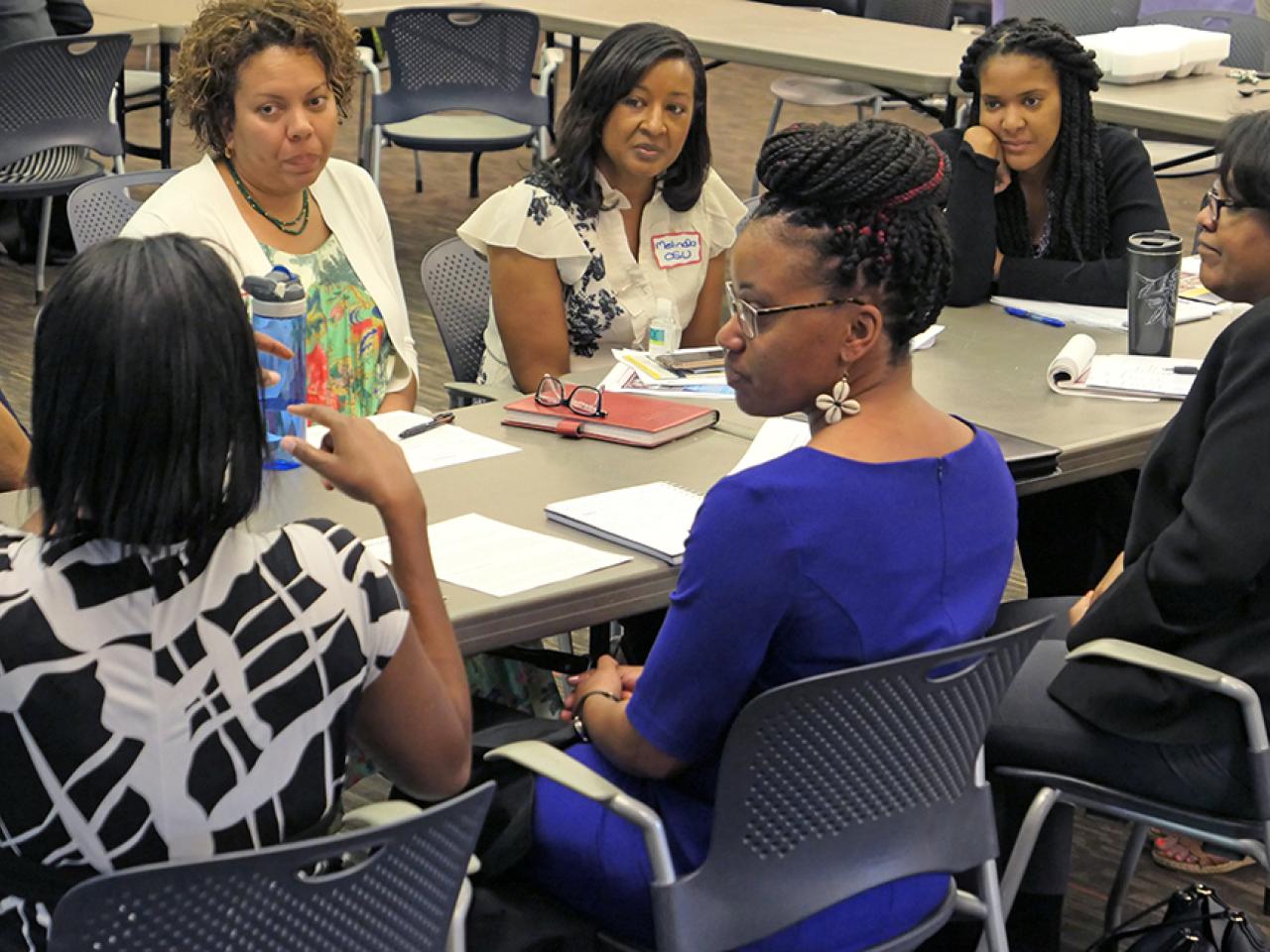Black women seated at a table having discussion