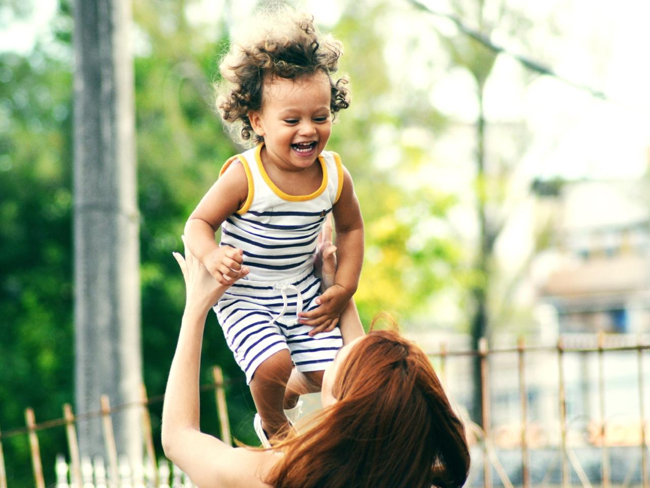 Young mother holding child up above her head