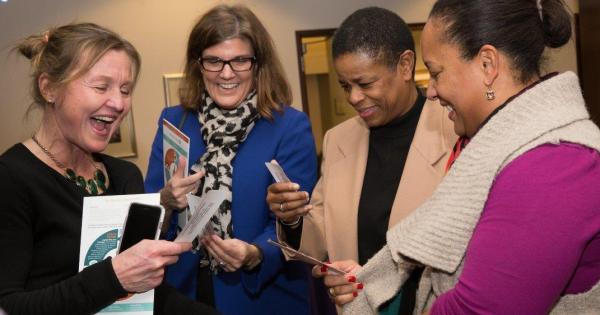 Four women standing in group viewing photos