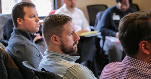 Five men sitting in a larger circle listening to workshop presenter