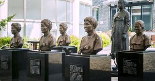 Bronze busts of Korean comfort women mounted on black podiums in two rows